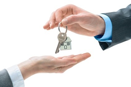 Man is handing a house key to other hands. Concept of real estate and deal